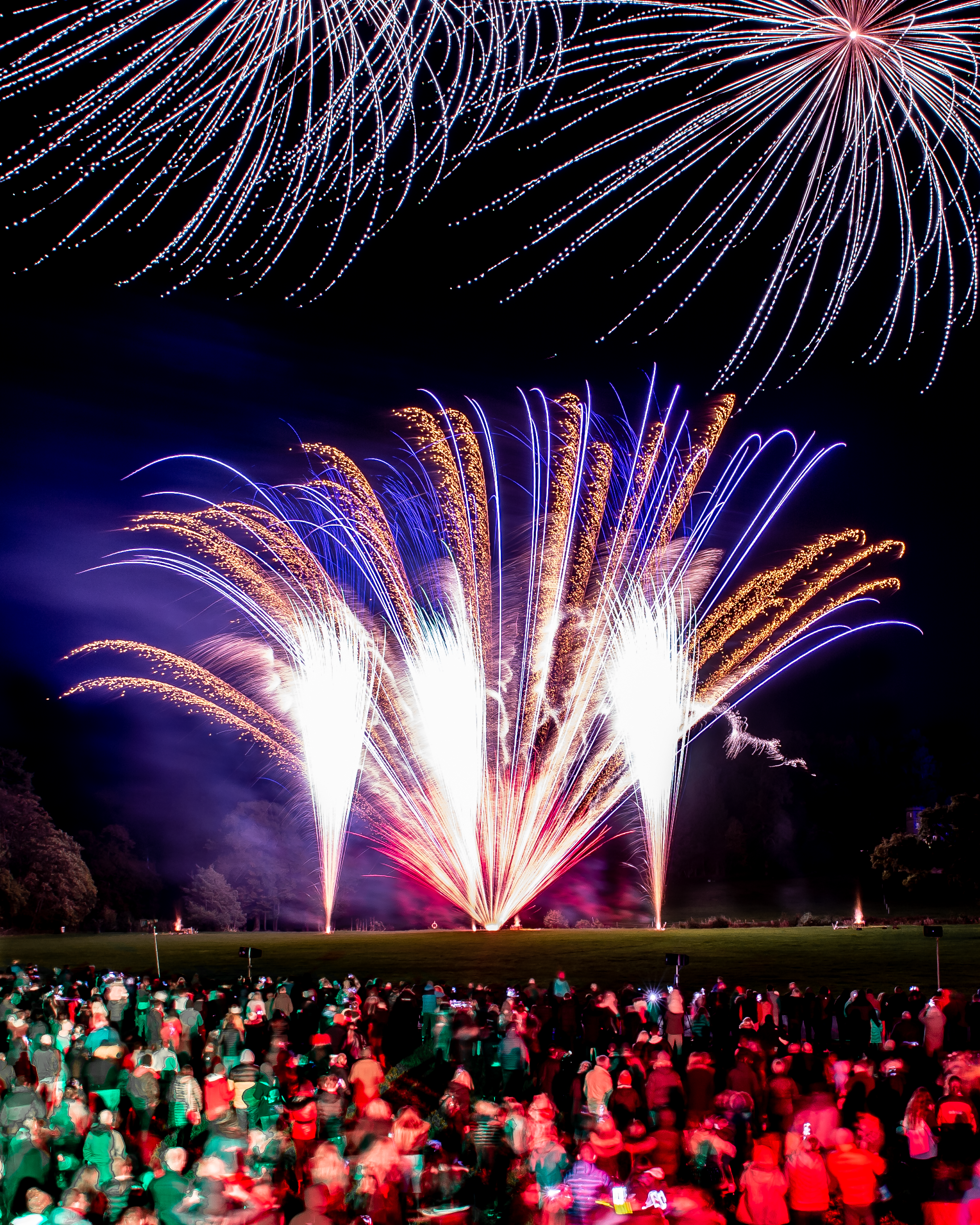 Bolesworth Estate firework display lighting up the night sky with colorful bursts, with busy crowds looking on in awe.