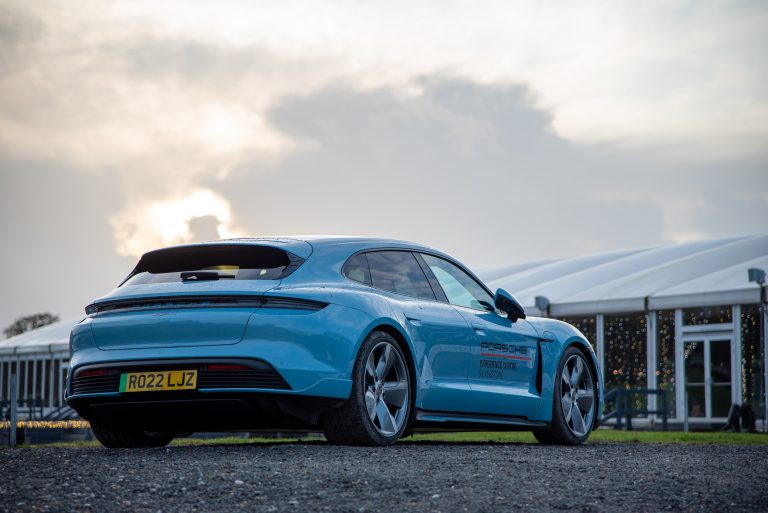 An blue Porsche sports car parked in the centre of a race track, with the Bolesworth marquee in the background.
