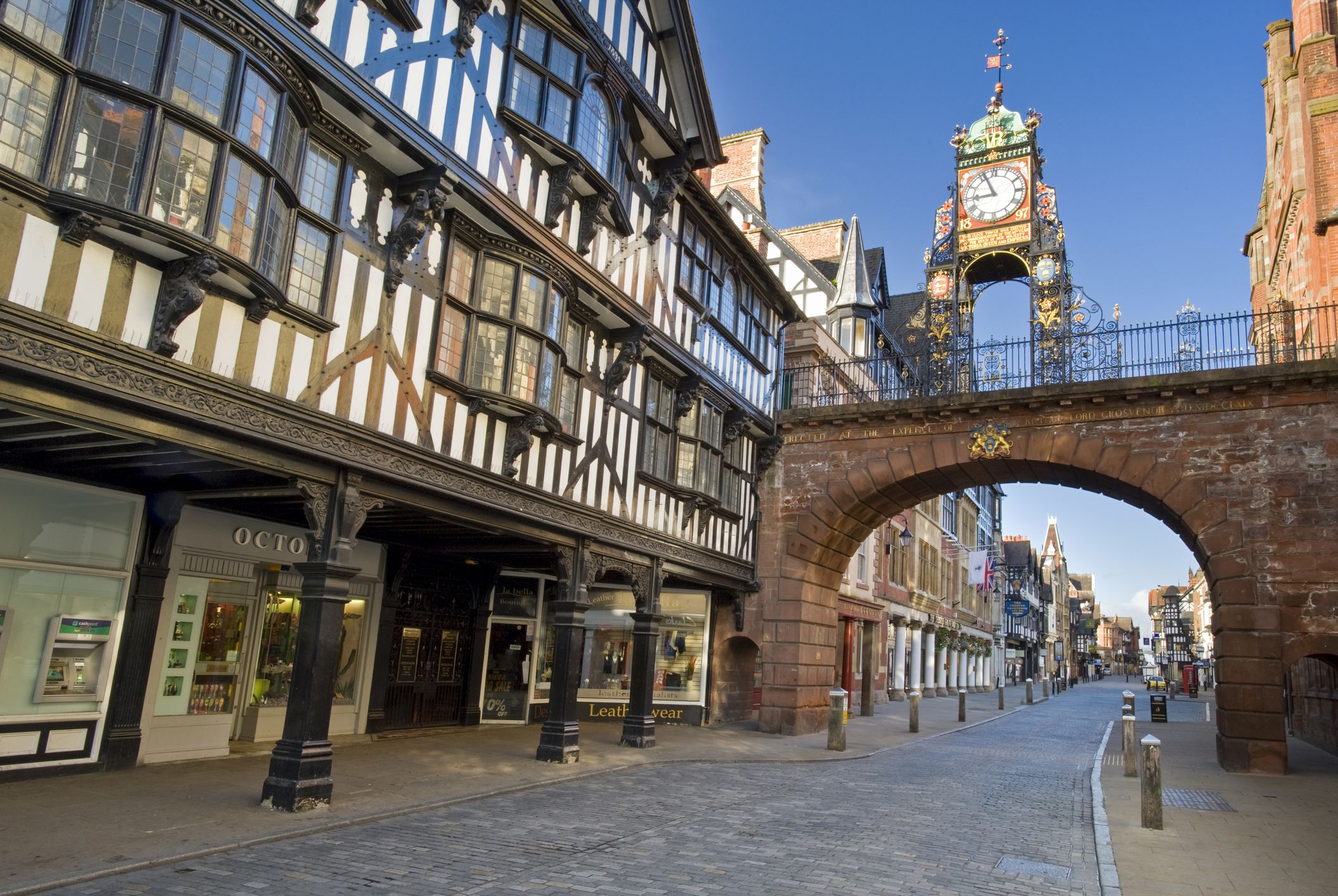 Historic Eastgate Clock in Chester, UK, standing above the medieval city walls with half-timbered Tudor-style buildings lining the streets.