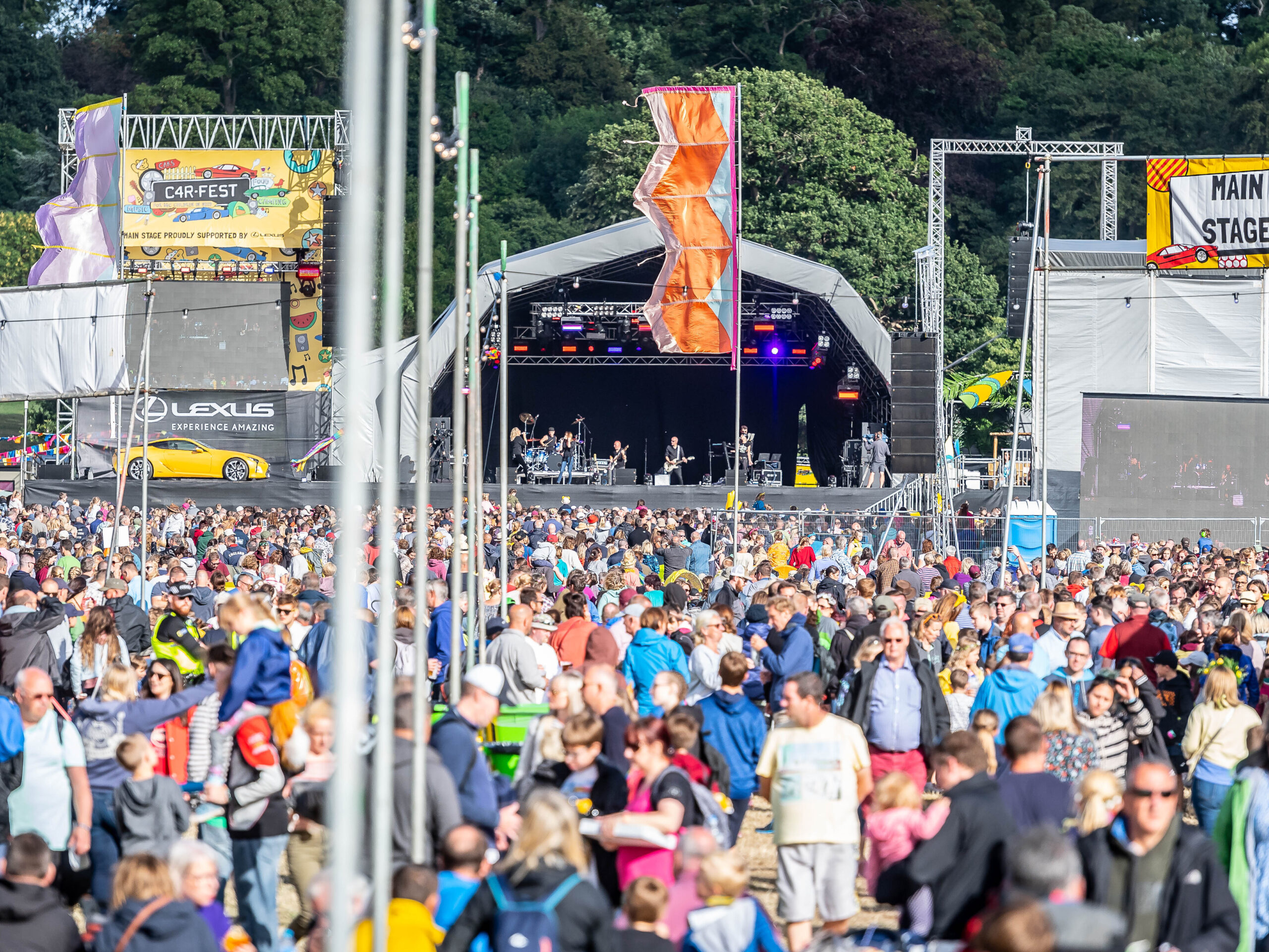 Large crowd enjoying live music at the main stage of CarFest at Bolesworth.